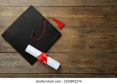 Graduation Hat And Diploma On Wooden Table, Flat Lay. Space For Text