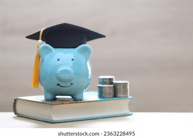 Graduation hat on blue piggy bank with stack of coins money on wooden background, Saving money for education concept  - Powered by Shutterstock