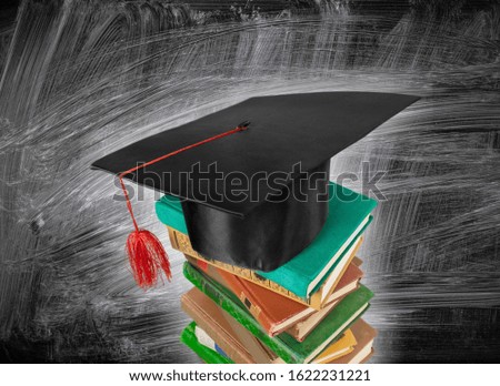 Graduation hat on a book stack on the blackboard background