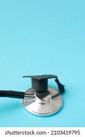 Graduation Hat On Doctor Stethoscope, Blue Background With Copy Space. Medical School, Health Care Education Or Doctor's University Degree Concept