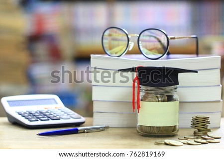 Graduation hat on the glass bottle on bookshelf in the library room background, Saving money for education concept