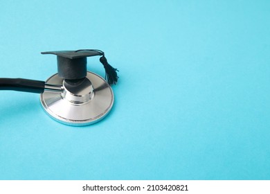 Graduation Hat On Stethoscope, Blue Background With Copy Space. Medical School, Health Care Education Or Doctor's University Degree Concept