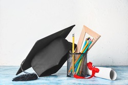 Graduation hat, stationery and diploma on table, a School & Education Photo by Pixel-Shot