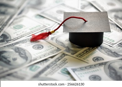Graduation mortar board cap on one hundred dollar bills concept for the cost of a college and university education - Shutterstock ID 256626130