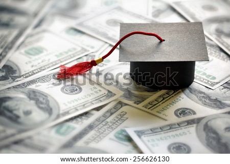 Graduation mortar board cap on one hundred dollar bills concept for the cost of a college and university education