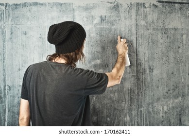 Graffiti Artist In Black Clothes Spraying The Wall/