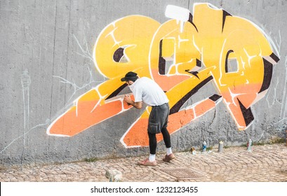 Graffiti artist covering his face while painting with color spray on the wall - Urban, street art, millennials generation, mural concept - Focus on his head - Shutterstock ID 1232123455