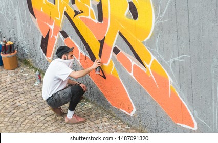 Graffiti Artist Covering His Face While Painting With Color Spray On The Wall - Urban, Street Art, Millennials Generation, Mural Concept - Focus On His Head