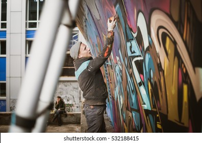 Graffiti Artist Painting With Aerosol Spray On The Wall