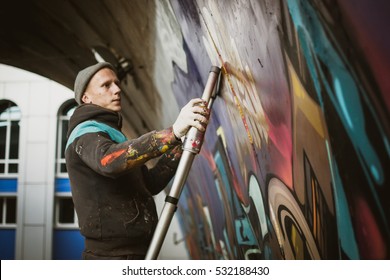 Graffiti Artist Painting With Aerosol Spray On The Wall