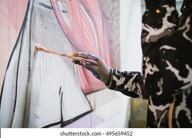 Graffiti artist painting with brush on the wall