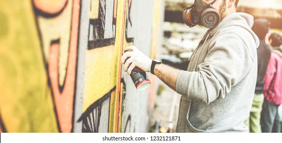 Graffiti artist painting with color spray on the wall for international competition - Urban, street art, millennials generation, mural concept - Focus on his hand
