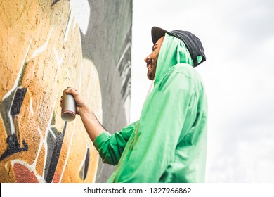 Graffiti Artist Painting With Color Spray On The Wall - Urban, Street Art, Millennials Generation, Mural Concept - Focus On His Hand