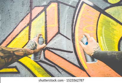 Graffiti Artist Painting With Color Spray On The Wall - Tattoed Writer At Work In Suburb Neighborhood - Urban, Street Art, Millennials Generation, Mural Concept - Focus On Spray Cans