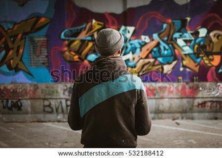 Graffiti artist standing near the wall