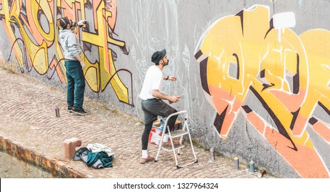 Graffiti Artists Friends Painting With Color Spray On The Wall For International Competition - Urban, Street Art, Millennials Generation, Mural Concept - Focus On Right Guy Face