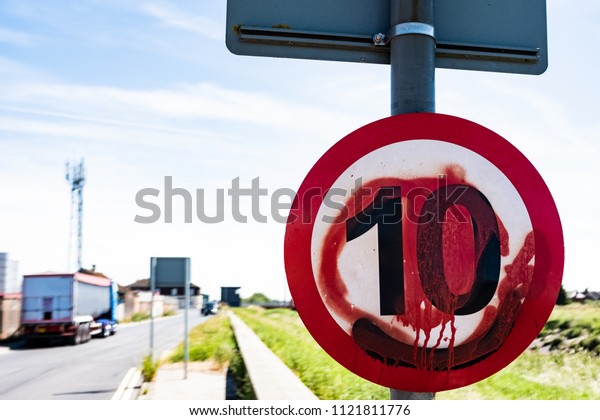 Graffiti\
covered road sign 10 miles an hour red\
paint