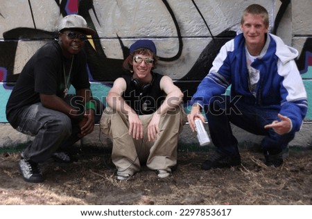Graffiti, street art and portrait of friends by wall with spray can for hip hop, fashion and urban. Smile, artist and painting with group of male teenagers in park for grunge, creative and style