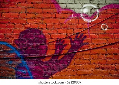 Graffiti wall in urban centers depicts a kid and bubbles with arms raised upwards in purple on a bright orange wall with ridges and black telephone wires running across the breadth of the shot - Shutterstock ID 62129809