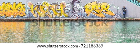 Graffiti writer at the end of his urban paint at river - concept of contemporary artist, lifestyle, street art - Warm filter 