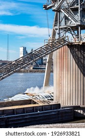 Grain elevator terminal spout loading grain corn into dry cargo bulk barge on Mississippi River, industry, food, raw, commodity, export, transport, marine, maritime, inland waterway, agriculture