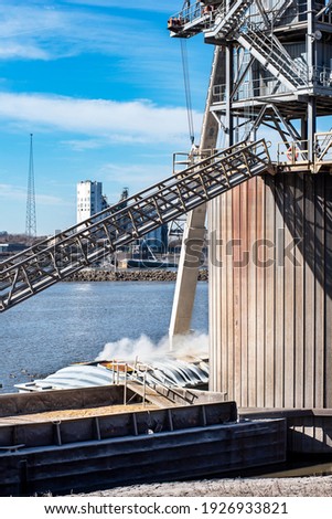 Grain elevator terminal spout loading grain corn into dry cargo bulk barge on Mississippi River, industry, food, raw, commodity, export, transport, marine, maritime, inland waterway, agriculture