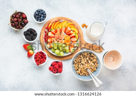 Grain free paleo style granola or vegan muesli made from nuts. Fruit berries platter, strawberries blueberries raspberries peach figs red currant, overhead view, selective focus