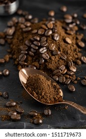 Grained Coffee Powder On Rose Gold Spoon And Coffee Beans Over Black Marble Surface.