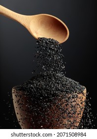 Grains of black sesame are poured with a wooden spoon in the bowl. Black sesame on a dark background. Copy space. - Shutterstock ID 2071508984