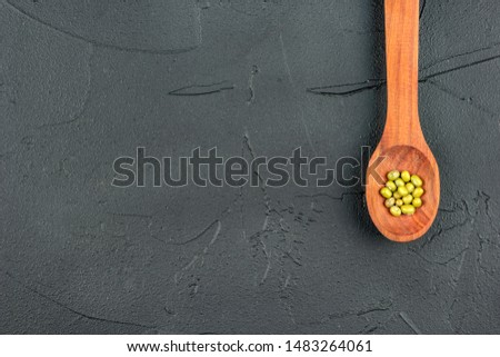 Grains of green mash in a wooden spoon on a dark background