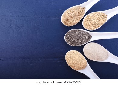 Grains Including, White Grain Quinoa, Psyllium Husk Powder, Black Chia, Wheat Germ, And Ground LSA Mix, On Dark Blue Wood Grain Table, With Copy Space. 