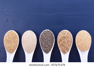 Grains Including, White Grain Quinoa, Psyllium Husk Powder, Black Chia, Wheat Germ, And Ground LSA Mix, On Dark Blue Wood Grain Table, With Copy Space. 