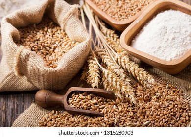 grains and wheat ears on a wooden table, top view