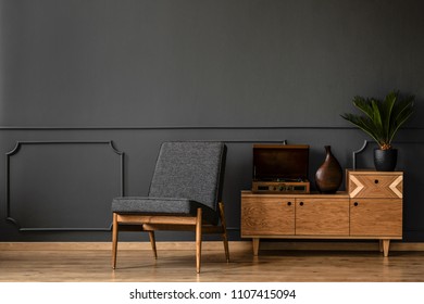 A gramophone on wooden cabinet and black chair in dark retro room interior