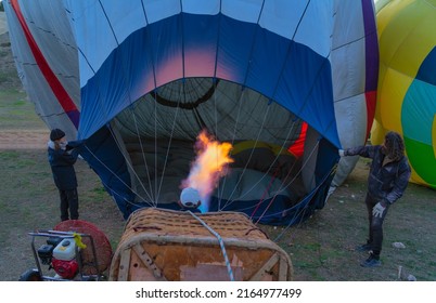 Granada, Spain 29 January 2022. Two People Hold The Hot Air Balloon And Another Person Heats The Balloon With A Large Flame Of Fire.