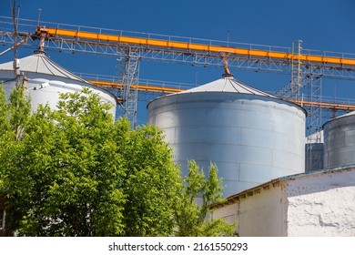 Granary elevator, Ukrainian grain storage on blue sky and green trees background. International wheat, seed and corn supplier. War 2022 in Ukraine - Shutterstock ID 2161550293