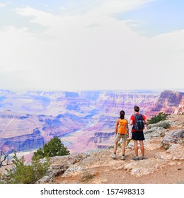 Grand Canyon - People Hiking Looking At View. Hiker Couple Walking On South Rim Trail Of Grand Canyon, Arizona, USA. Beautiful American Landscape.