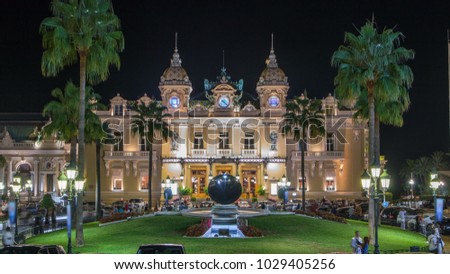 Grand Casino in Monte Carlo night timelapse, Monaco. historical building and square in front of it. Front view with entrance. Palms on the side. Evening illumination