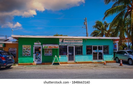 Grand Cayman, Cayman Islands, July 2020, View Of A Small Food Store And A Car Dealer Office In A Colorful Building In George Town