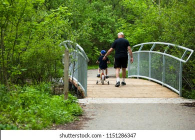 Grand Dad Supporting His Grandson Child Learning How To Ride A Bike