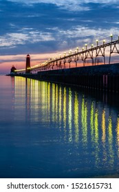 Grand Haven Lighthouse at sunset with catwalk lights reflected in Lake Michigan