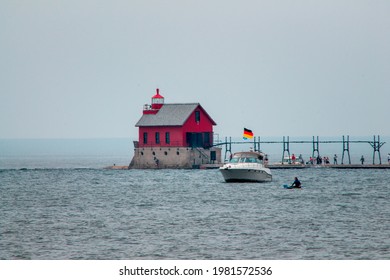 Grand Haven, MI, USA - May 18th 2019:  Red building at the end of the pier and lighthouse in Grand Haven Michigan