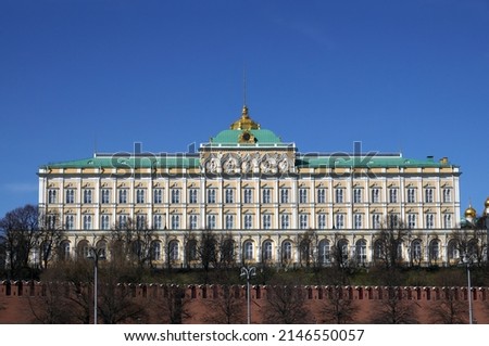 Grand Kremlin Palace with spire on cupola behinf red brick Kremlin wall cloudless sunny bright day