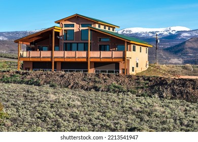 Grand Lake, Colorado, USA, May 2022, New Modern Wood Frame Log Cabin Home In Rural Country With Snow Peak Mountains In Background