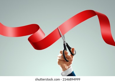 Grand opening with red ribbon and scissors. A businessman's hand holds scissors cuts a red ribbon on a light background. Close-up, copy space - Shutterstock ID 2146894999