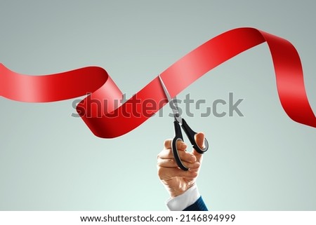 Grand opening with red ribbon and scissors. A businessman's hand holds scissors cuts a red ribbon on a light background. Close-up, copy space Stockfoto © 