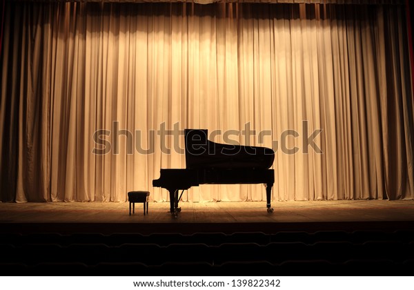 Grand piano at\
concert stage with brown\
curtain