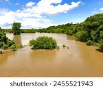 Grand River, Brantford, Ontario, Canada. After the rain. Flood flooded flooding. Sunny summer day blue sky clouds. Muddy water. Trees. Cockshutt Bridge. Force of nature.