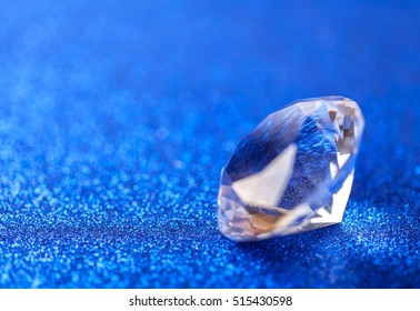 Grand royal pure diamond on blue sparkling sequins background, macro . Big brilliant closeup.