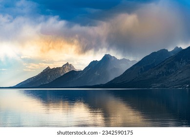The Grand Teton National Park hills reflected in the water below at a sunset in Wyoming, United States